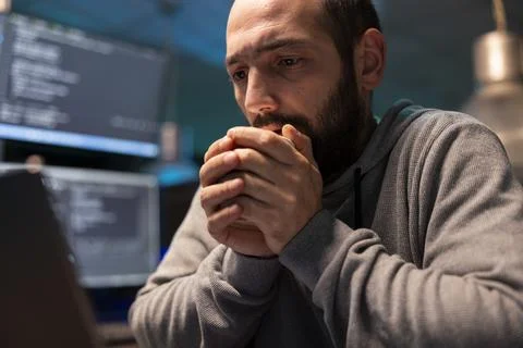 Concerned programmer stares at computer display with coffee cup in hand Stock-Fotos