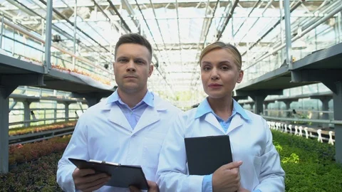 Concerned scientists looking camera in greenhouse, agriculture quality control Stock-Footage 118925191