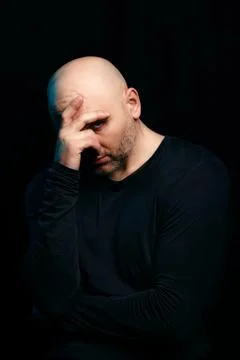 Concerned white bald man with problems in thought on a black background. The  Foto stock