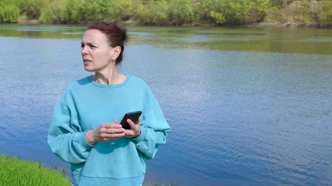 Concerned woman using smartphone searching for gps signal Vídeos de archivo 345062999