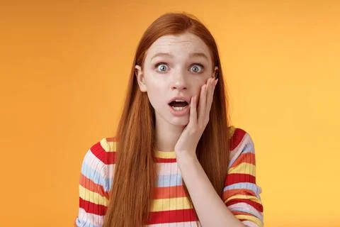 Concerned worried ginger girl blue eyes drop jaw gasping touch cheek confu... Stock Photos