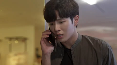Concerned young asian man talking on phone 스톡 동영상 333805094