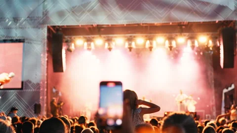 Concert crowd captivated, dancing under vibrant lights with dynamic stage setup Stock Footage 277613777