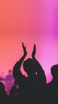 Concert crowd clapping beneath pink stage light Foto stock