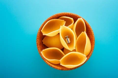 Conchiglie rigate pasta or seashell macaroni in brown bowl on blue background Stock Photos