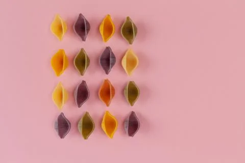 Conchiglie Rigate pasta shells in rows on pink background. Top view with copy 写真素材