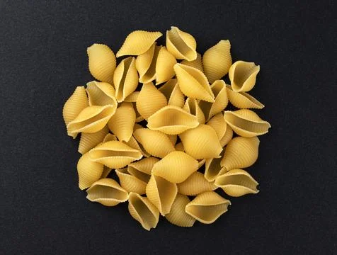 Conchiglie rigate. Raw striped shell pasta on black background, top view Stock Photos