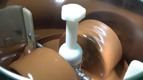 A conching machine keeps chocolate liquid. Chocolate turning in a steel bowl Video stock 88942179