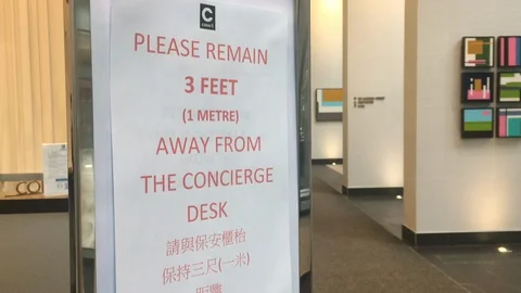 Concierge instructions in a lobby to keep distance during the COVID-19 pandemic Stock Footage 127851350