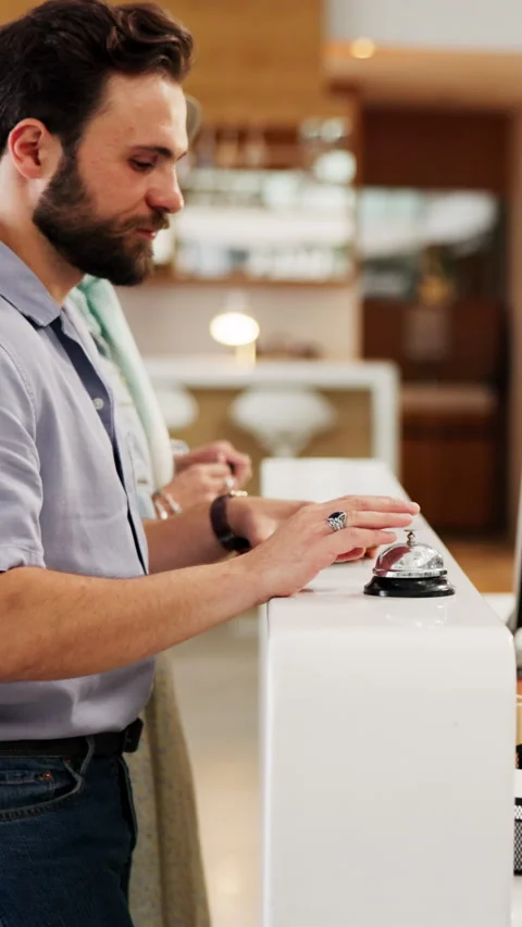 Concierge, sign in and bell with man at front desk for hospitality, booking or Stock Footage 335353957
