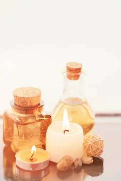 Concise spa composition with oil flasks and candles on beige background. Stock Photos