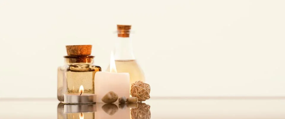 Concise spa composition with oil flasks and candles on beige background. Stock Photos