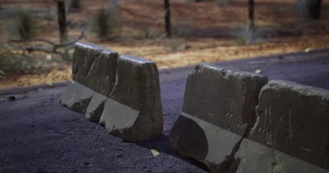 Concrete barriers block access on a remote desert road during dusk Stock Footage 303743358