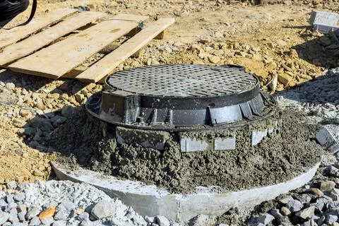 Concrete is being applied to stabilize blocks forming upper edge of manhole for Stock Photos