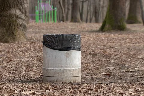 Concrete bin with garbage bag inside in city park in spring. Foto stock