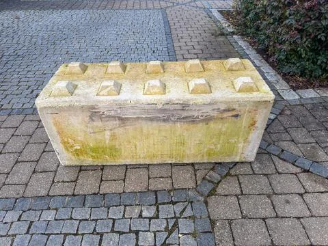 Concrete block barrier on cobblestone pavement with moss Stock Photos