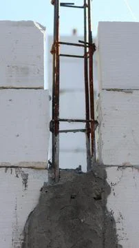 Concrete block wall under construction with exposed steel rebar and fresh m.. Stock Photos