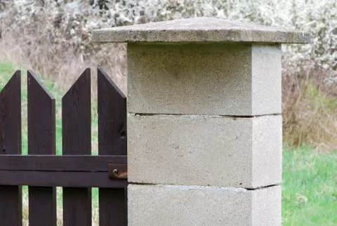 Concrete blocks side post of brown wooden fence. Stock Photos