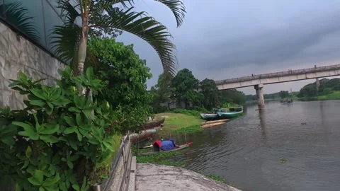 Concrete bridge over river with small wooden boats near bank at dusk Stock Footage 342157075