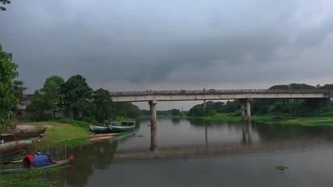 Concrete bridge over river with small wooden boats near bank at dusk Stock Footage 342157449