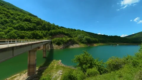 Concrete bridge spans a calm, turquoise lake. Zavoj Lake, Serbia Stock Footage 337492664