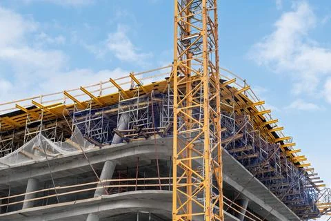 A concrete building under active construction is surrounded by scaffolding .. Stock Photos