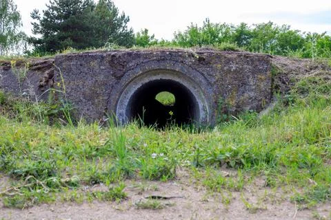 Concrete culvert and drainage system outlet open onto a green grassy field... Stock Photos