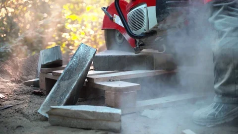 Concrete cutting machine. A worker in the park area cuts heavy slabs for a Stock Footage 120865756