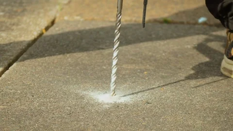 Concrete drilling process with hammer drill bit penetrating pavement surface Stock Footage 342501847