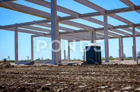 Concrete edifice under construction with mobile plastic toilet Stock Photos