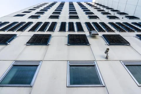 The concrete facade of a prison. The windows are fitted with bars so that the Stock Photos