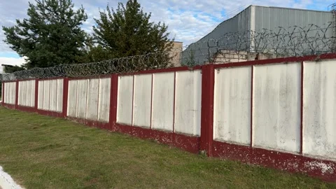 Concrete fence with red frames and razor wire  Stock Footage 340515275