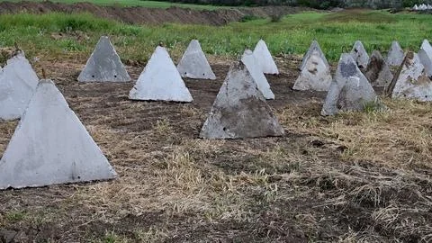 Concrete fortifications dragons teeth on the field. Stock Photos