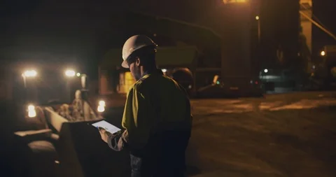 Concrete manufactory industry workers using tablet outside factory late at night Stock Footage 124303928