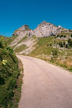 Concrete mountain road between alpine meadows and rocks, peaks of Tour de M.. Stock Photos