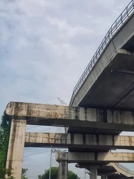 Concrete overpass structure with railing and support pillars stands under a c Fotos Stock