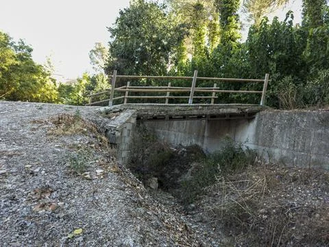 Concrete pedestrian bridge built over a dry ditch in a rural area with a wo.. 库存照片