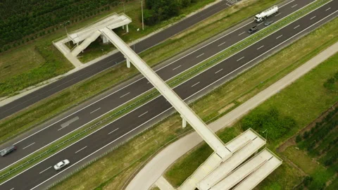 Concrete pedestrian overpass crosses a multi lane highway with active traffic Stock Footage 339075881