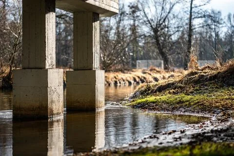 Concrete Pillars of Bridge Over River in Sunlight Foto stock