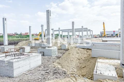 Concrete pillars of new edifice with a beautiful sky are placed on sandy grou Stock Photos