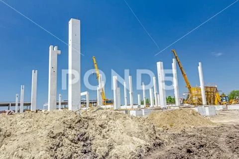 Concrete pillars of new edifice with a beautiful sky are placed on sandy grou Stock Photos