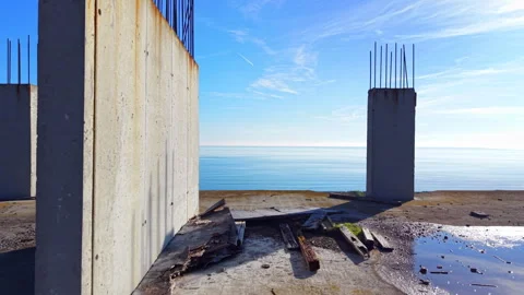 Concrete pillars of unfinished structure against blue sea Stock-Footage 334312124