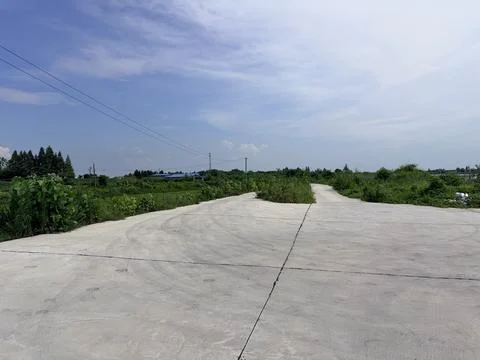 Concrete Road Leading to Green Fields Under Blue Sky Stock Photos