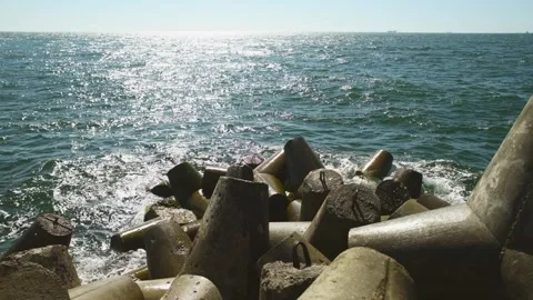 Concrete sea breakwater blocking waves under bright sunlight over deep blue.. Stock Footage 335942126