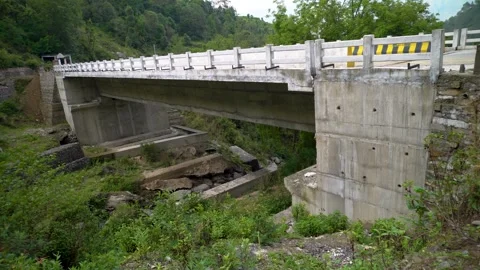 A concrete solid slab bridge connecting two small hills at the base in the .. Stock Footage 281093177