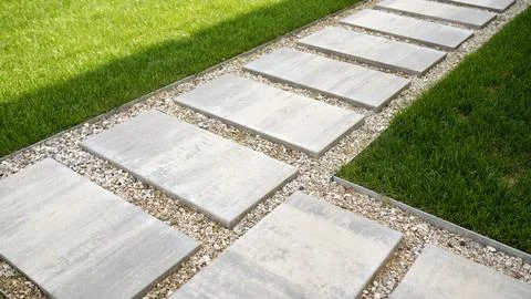 Concrete stepping stones path through green lawn with gravel edges Stock Photos