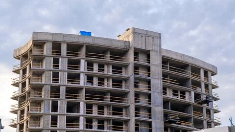 Concrete structure rises against cloudy sky. Windows frame empty spaces for.. Foto stock