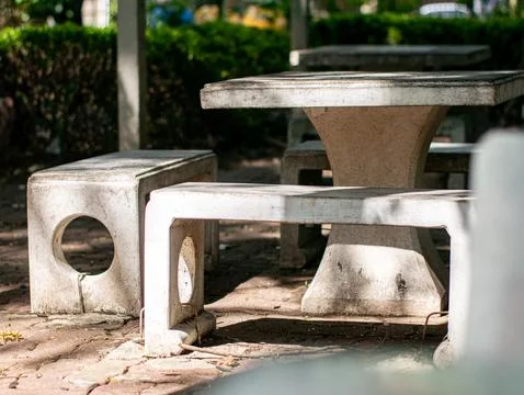 Concrete Table and Bench Set in Sunlit Park with Green Hedge Background Stock Photos