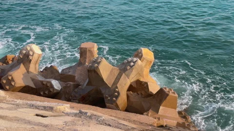 Concrete tetrapod breakwater blocks with waves splashing along coastal seawall Видео 342495134