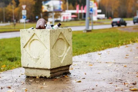 Concrete trash bin with empty bottles on road background Stock Photos